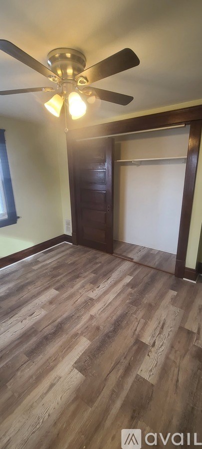 A room with a ceiling fan and wooden flooring.