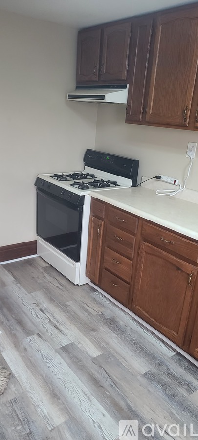 A kitchen with a black stove top oven and wooden cabinets.