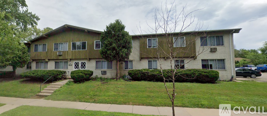 A two-story apartment building with a green lawn in front.