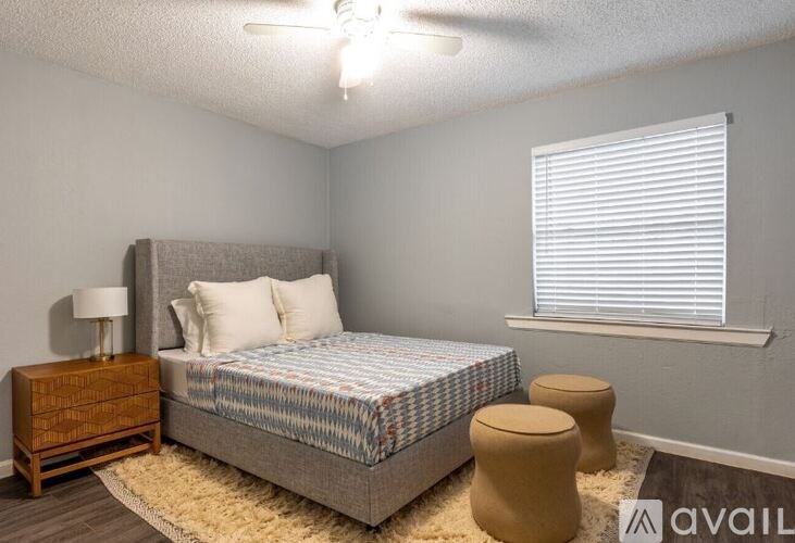 A bedroom with a bed, nightstand, and window with blinds.