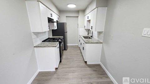 A kitchen with white cabinets and a black stove top oven.