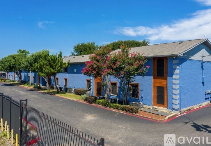 A blue building with a brown door and windows is surrounded by a black fence.