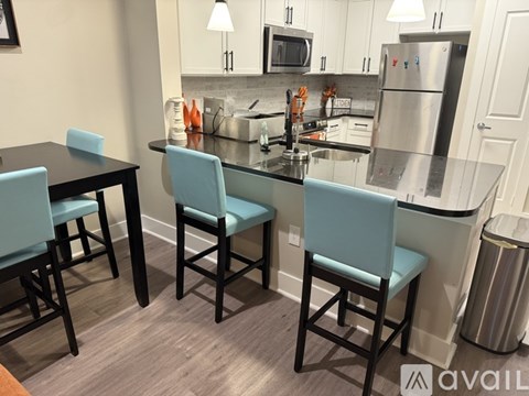 A kitchen with a black table and blue chairs.