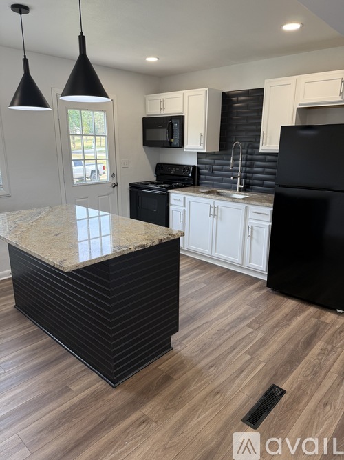 A kitchen with a black refrigerator and white cabinets.