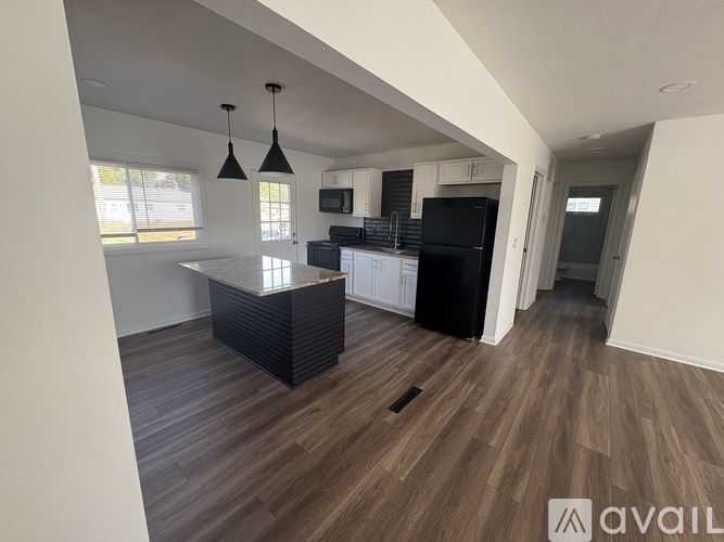 A kitchen with a black countertop and a black fridge.
