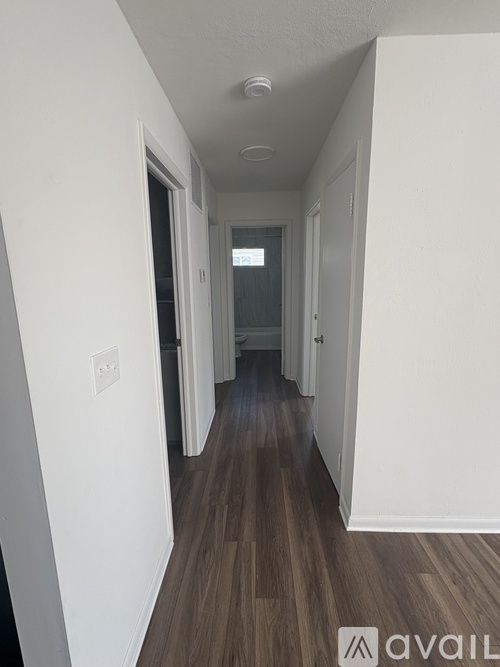A long hallway with wood floors and white walls.