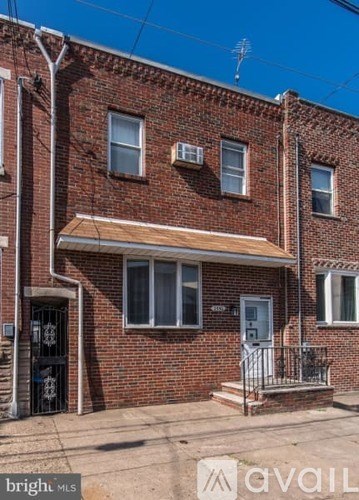 A red brick house with a white door and a balcony.