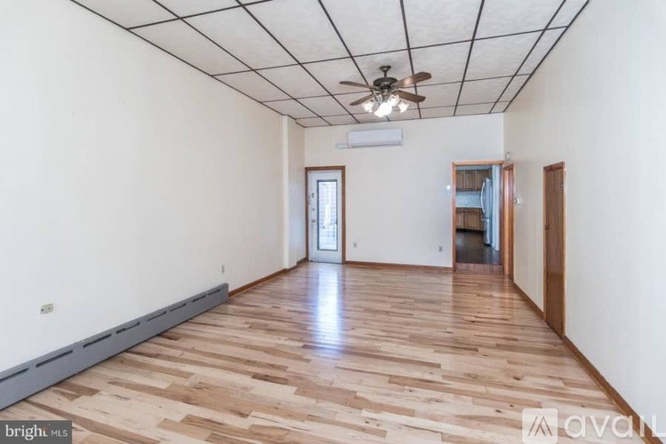A room with wooden flooring and a ceiling fan.