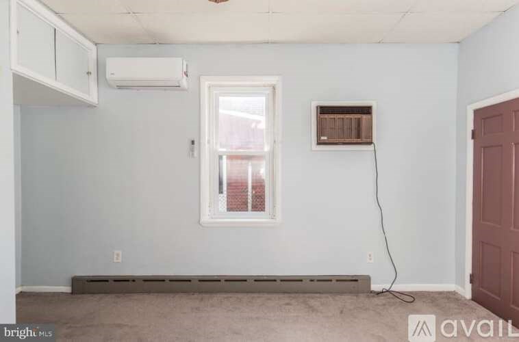 A room with a window, air conditioner, and a wall-mounted heater.