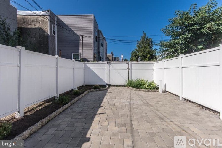 A white fence runs along the side of a brick pathway.