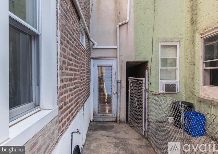 A narrow alley with a brick wall on one side and a chain link fence on the other.