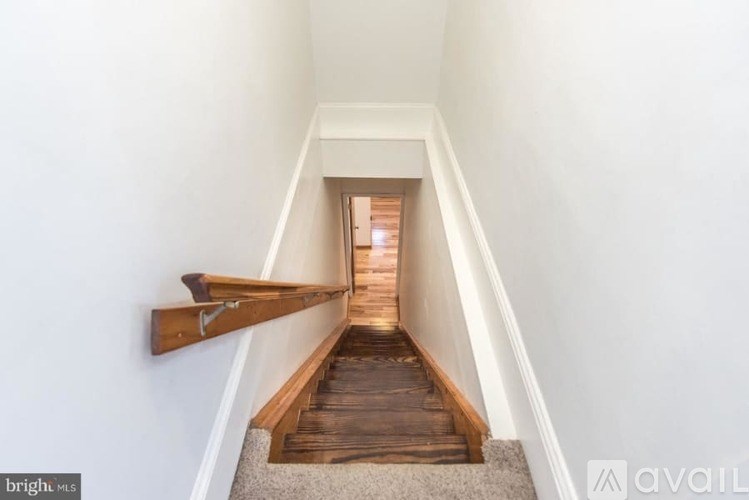 A long hallway with a wooden staircase leading to a door at the end.