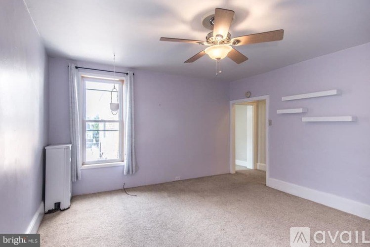 A room with a ceiling fan and a window with a view of a building outside.