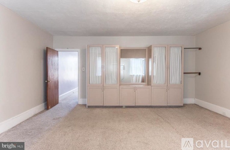 A room with a carpeted floor and a set of wardrobes.