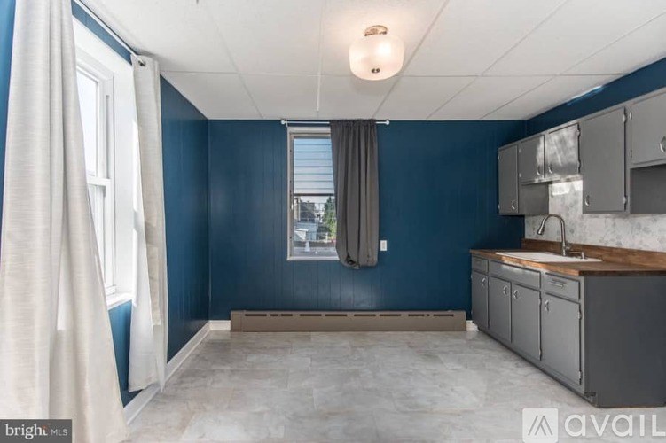 A kitchen with blue walls and a window with curtains.