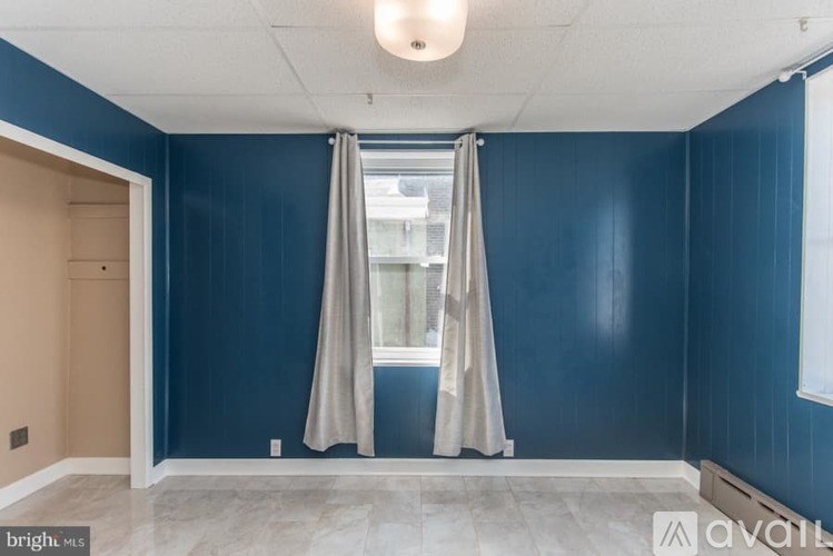 A room with blue walls and a window with curtains.