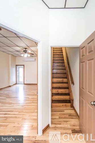 A room with wooden floors and a staircase leading to another room.