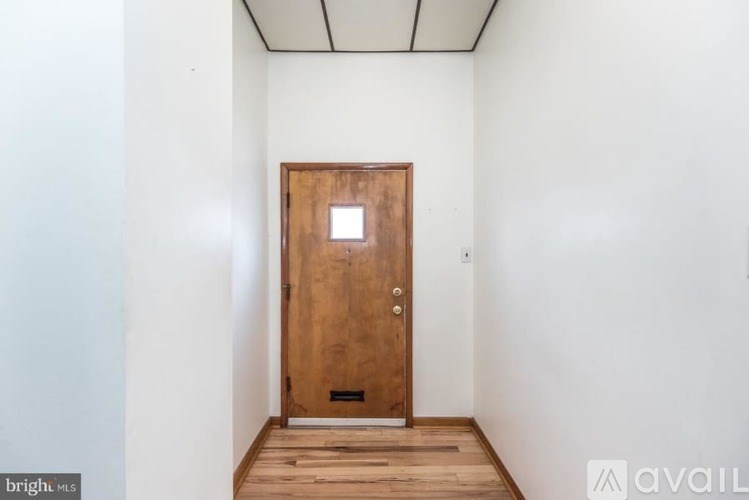 A room with a wooden door and a white wall.
