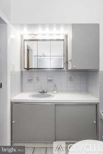 A bathroom with a sink, mirror, and cabinet.