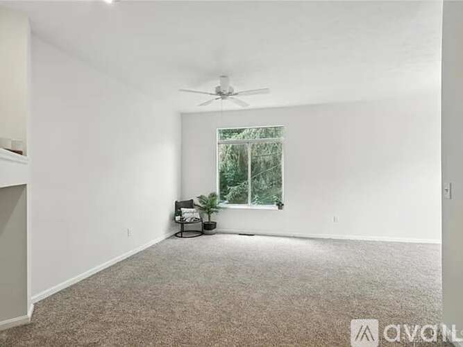 A room with a ceiling fan and a window with a view of trees.