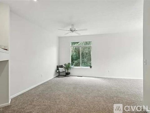 A room with a ceiling fan and a window with a view of trees.
