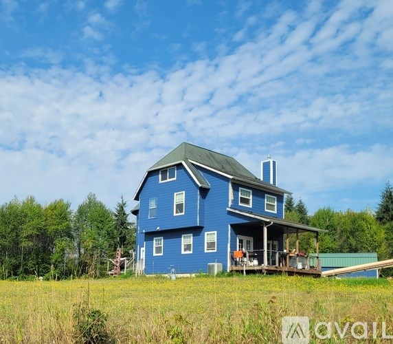 A blue house with a porch and a deck in front of it.