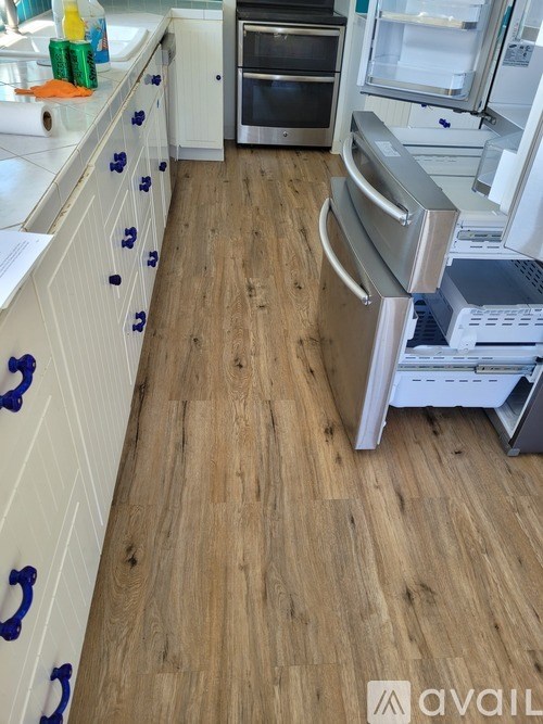 A kitchen with wooden floors and white cabinets.