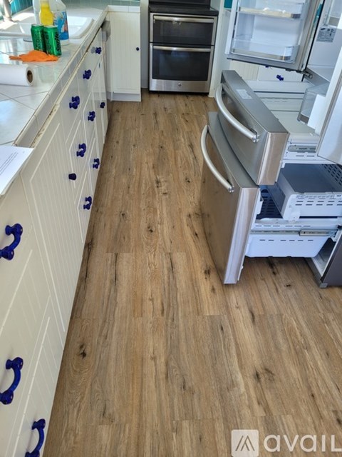 A kitchen with wooden floors and white cabinets.