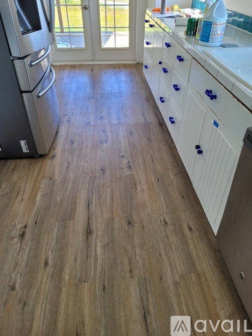 A kitchen with a wooden floor and white cabinets.