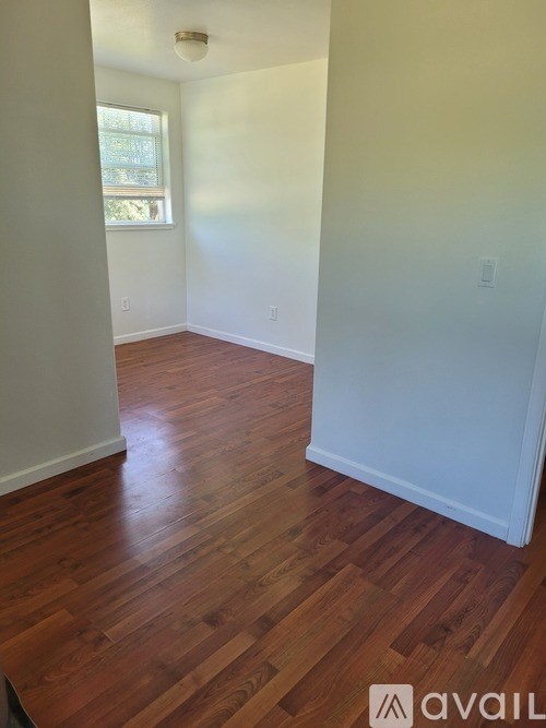 A room with wooden flooring and white walls.