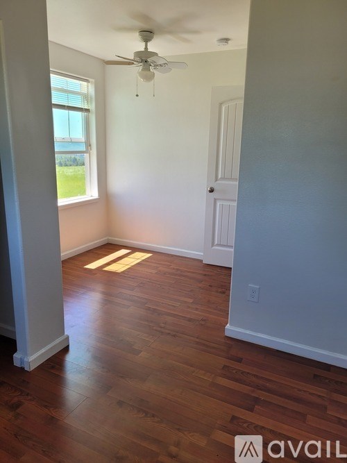 A room with a ceiling fan and wooden floors.