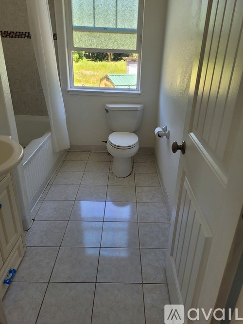 A bathroom with a toilet, a window, and a white door.