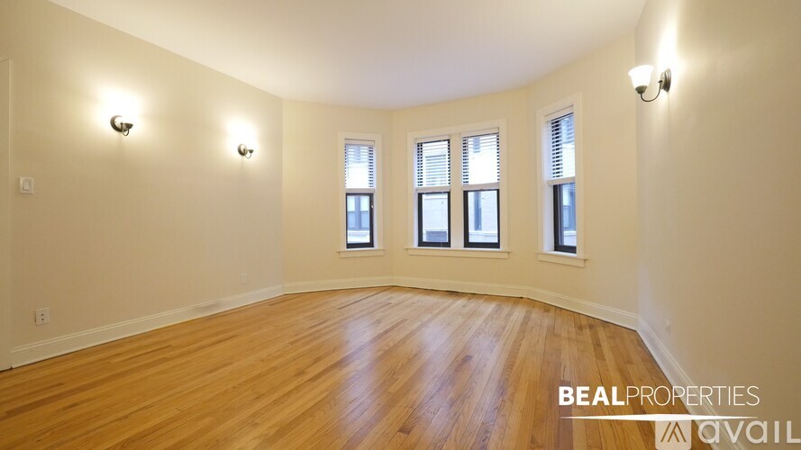A room with wooden floors and three windows.