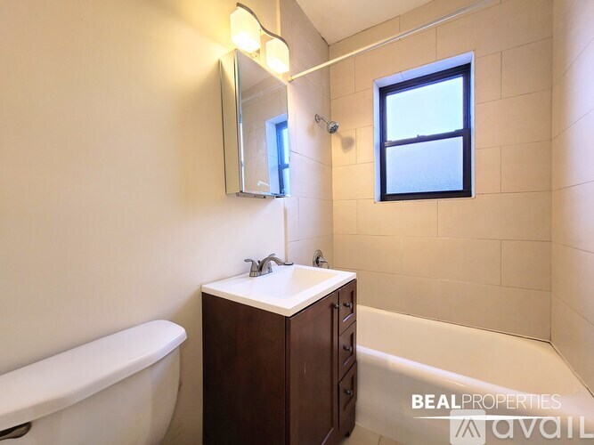 A bathroom with a white tub, a sink with a mirror above it, and a window.