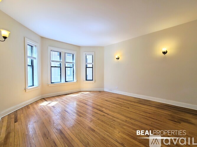 A room with wooden floors and three windows.