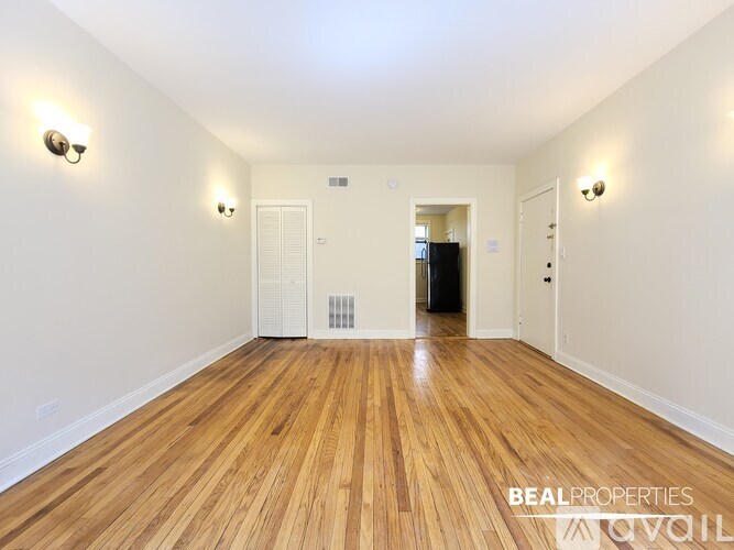A spacious room with wooden flooring and white walls.