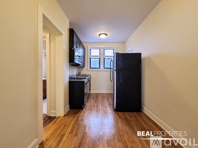 A kitchen with a black fridge and wooden floors.