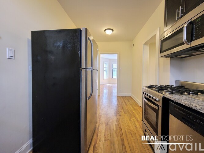 A kitchen with a black fridge, stove and microwave.