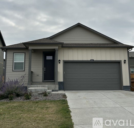 A house with a grey garage door and a black front door.