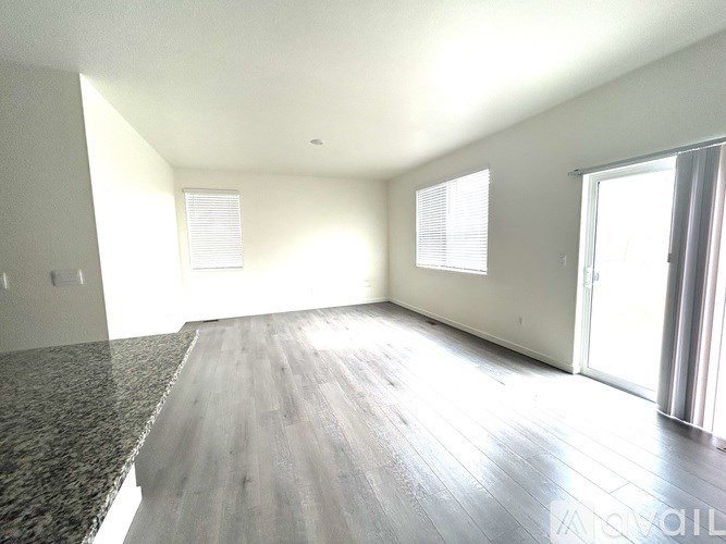 A spacious room with wooden flooring and a large window.