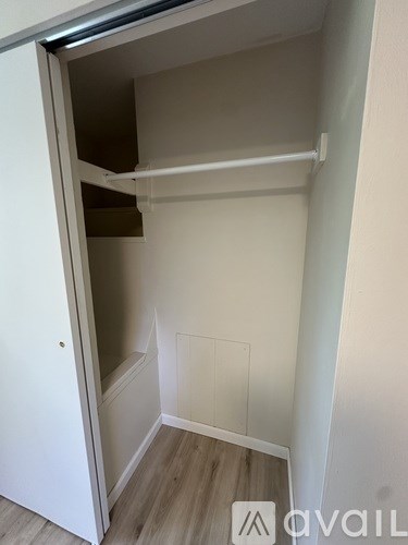 A white closet with a shelf and a door open.