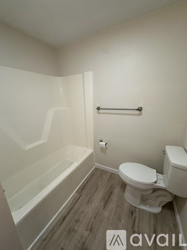 A white bathroom with a toilet, tub, and towel rack.