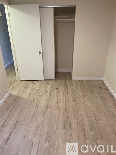 A room with a white door and wooden flooring.