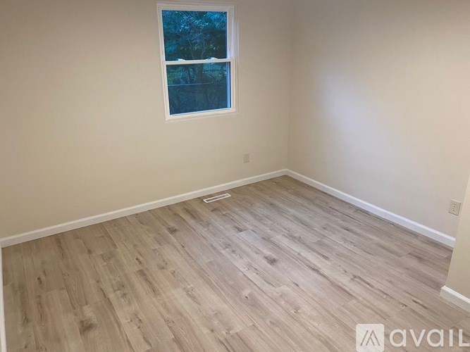 A room with a window and wooden flooring.