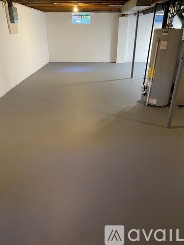 A room with a grey floor and white walls, with a wooden ceiling and a window.