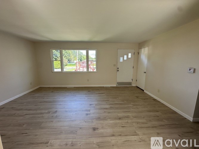 A room with wooden flooring and white walls is available for rent or sale.