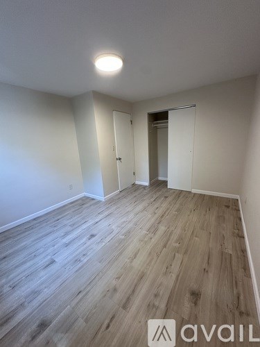 A room with wooden flooring and white walls.