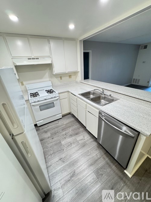 A kitchen with a stove, sink, and refrigerator.