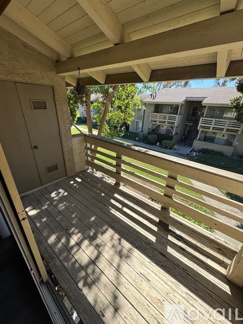 A wooden deck with a view of a house and trees.