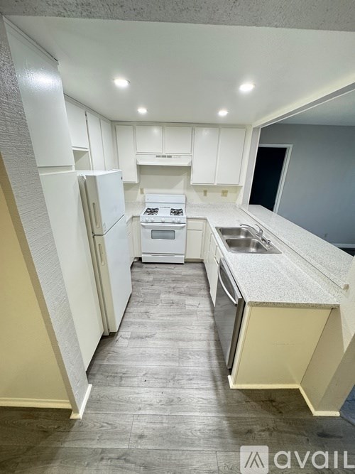 A kitchen with white cabinets and a white fridge.